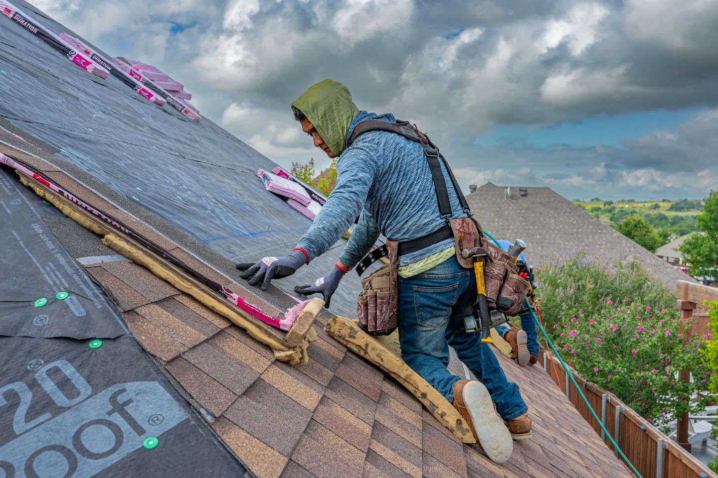 A roofer aligning asphalt shingles over underlayment on a residential roof